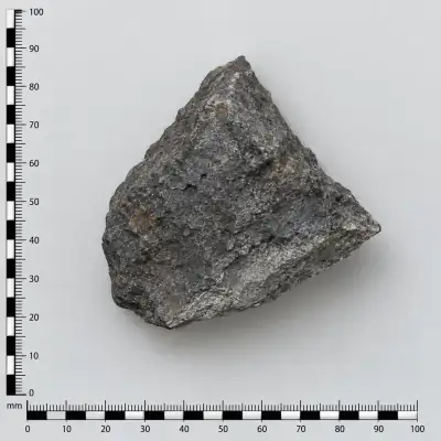 Customer specimen 01: angular charcoal stone, photographed beside a millimeter scale