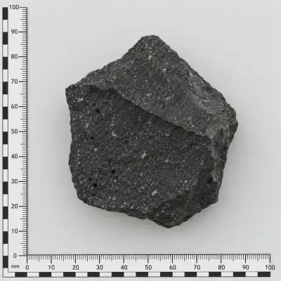 Customer specimen 03: speckled black angular rock, photographed beside a millimeter scale