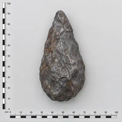 Customer specimen 04: metallic gray teardrop, photographed beside a millimeter scale