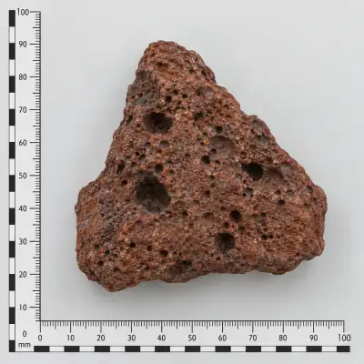 Customer specimen 07: reddish vesicular rock, photographed beside a millimeter scale
