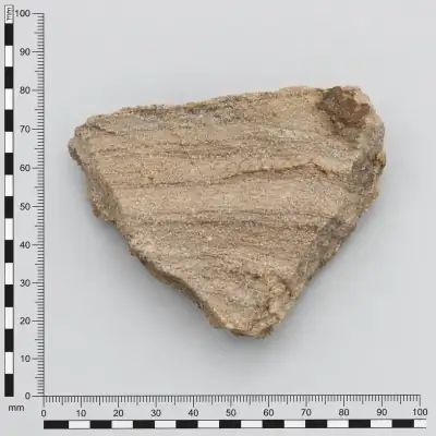 Customer specimen 15: tan granular fragment, photographed beside a millimeter scale