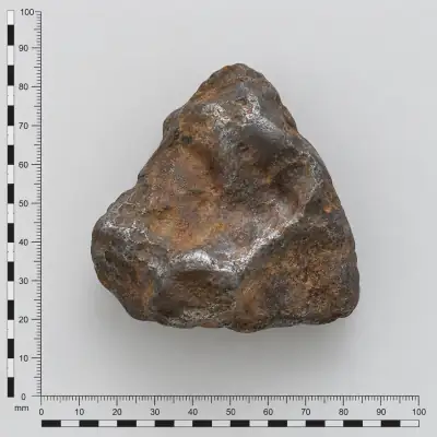 Customer specimen 20: rusty metallic pitted nugget, photographed beside a millimeter scale